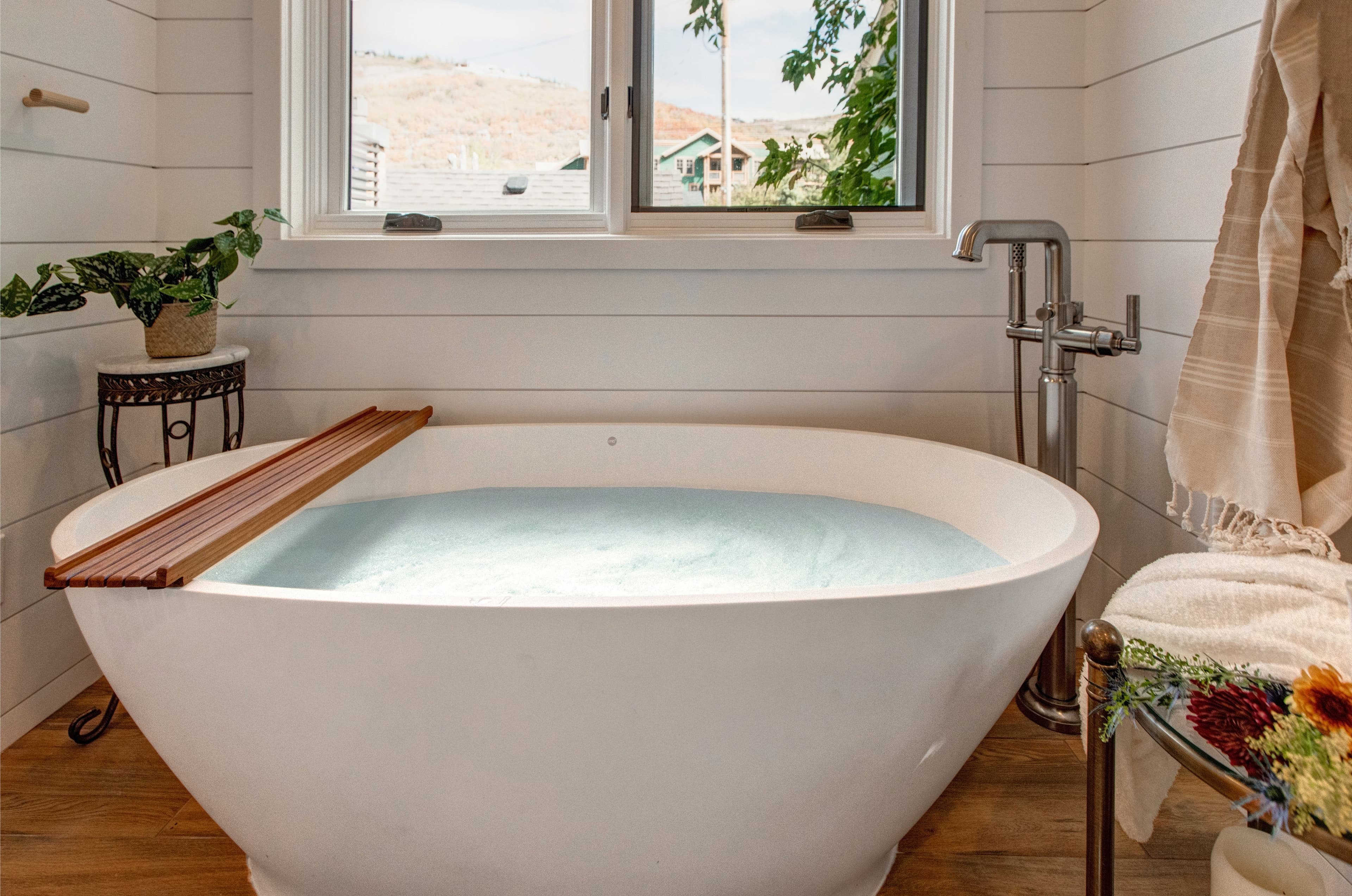 Lofted bedroom in detached guest suite, with a queen bed next to standalone bathtub.