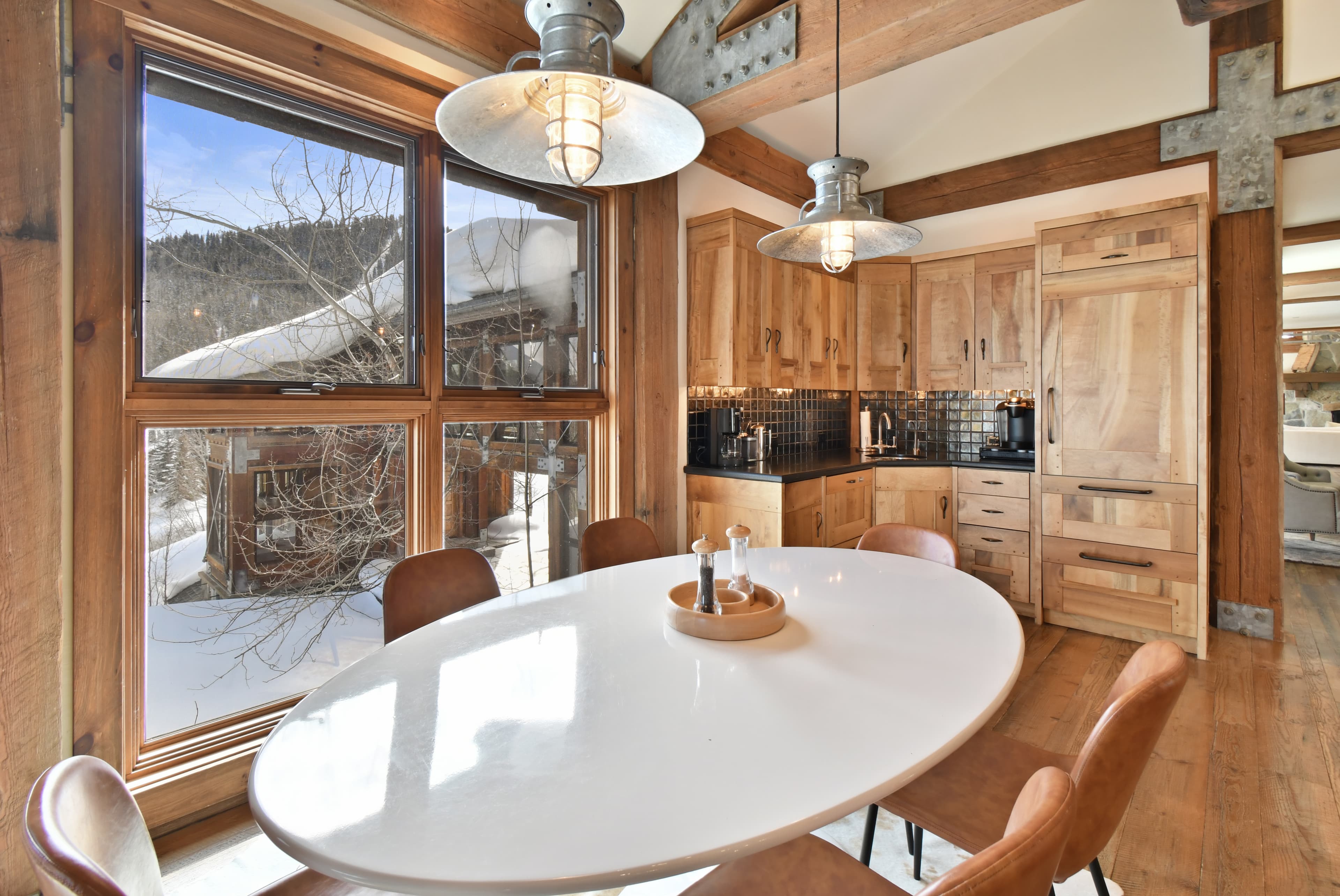 The dining table of the kitchen, with the wet bar visible in the background and a window to a snowy outdoors.