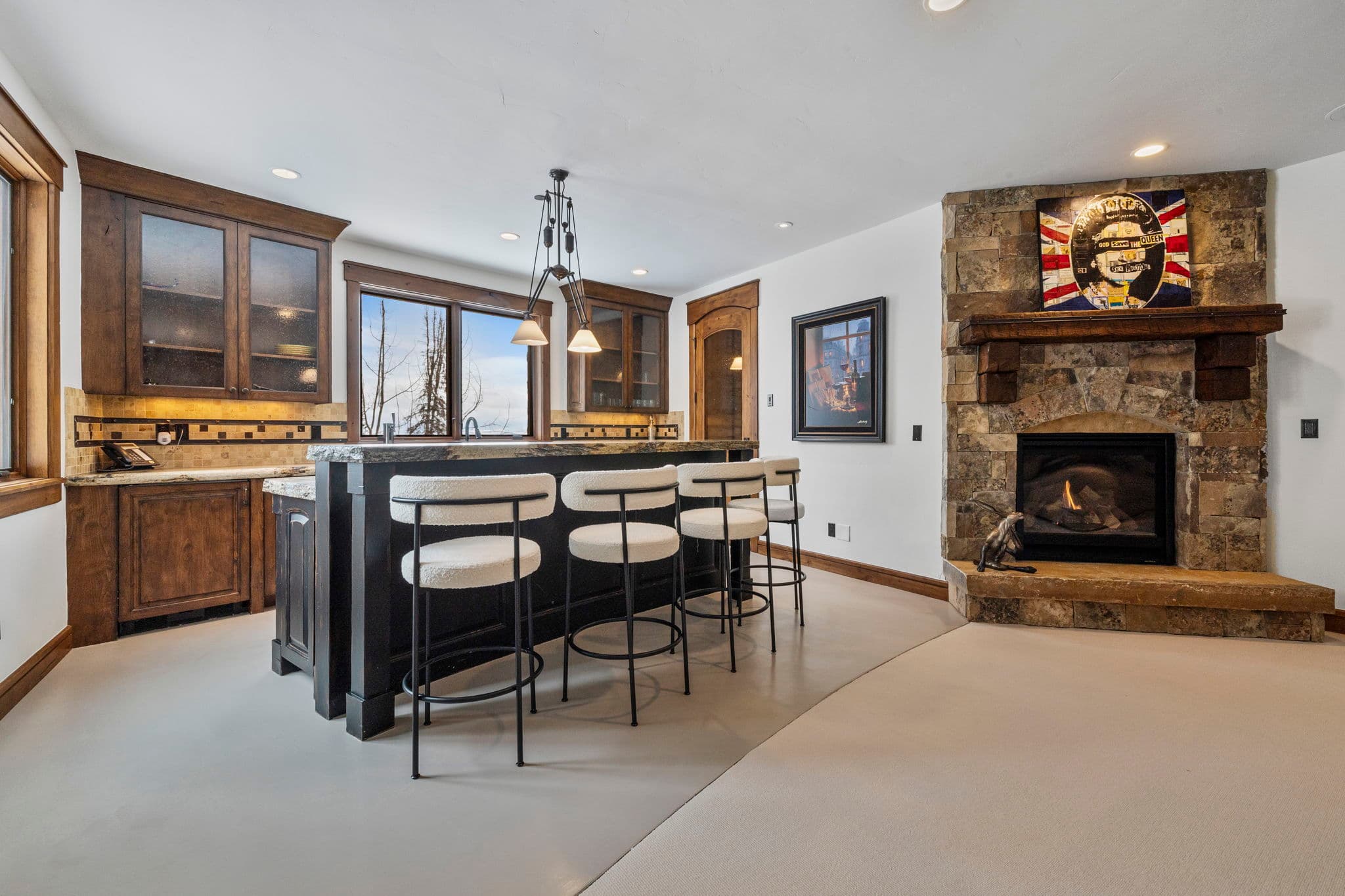 a view of the bar in the game room with sink, bar stools, and large fireplace